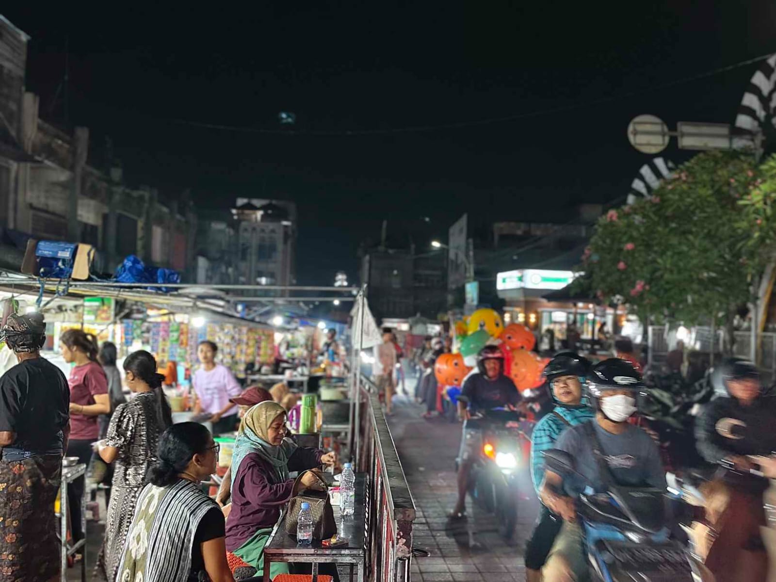 Suasana pasar malam yang ramai dengan pedagang kuliner, pakaian, minuman, dan aksesori.